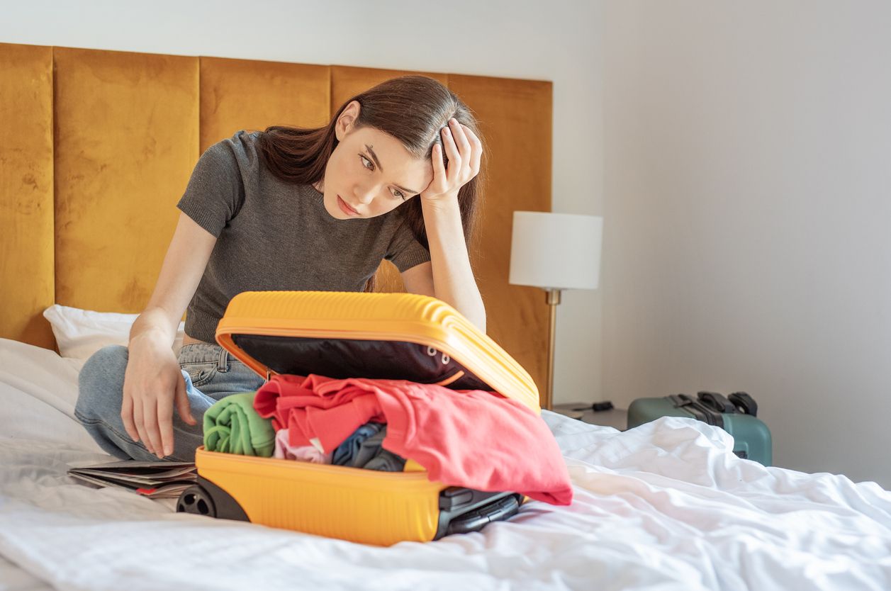 Traveler overpacking clothes into suitcase before vacation