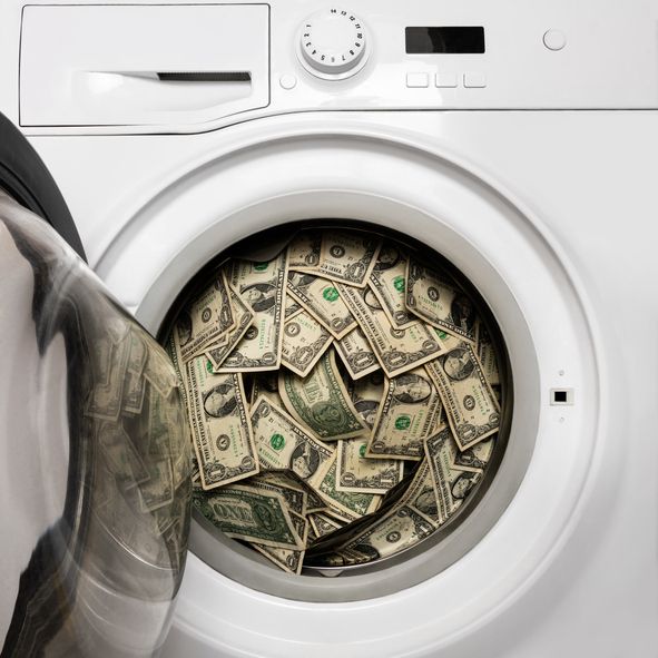 Load of money inside a washig machine symbolizing the hidden cost of home laundry