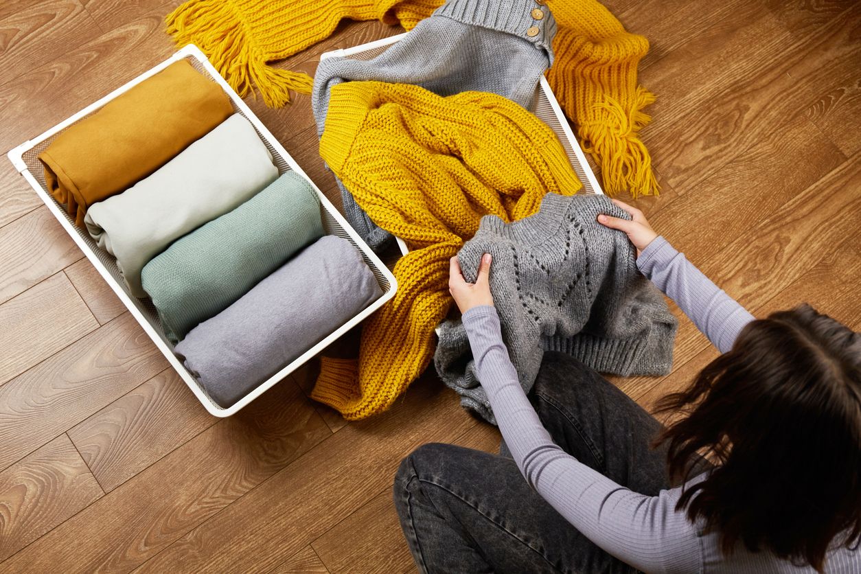 Fall hats, scarves, and gloves stored in a clear plastic container before seasonal cleaning