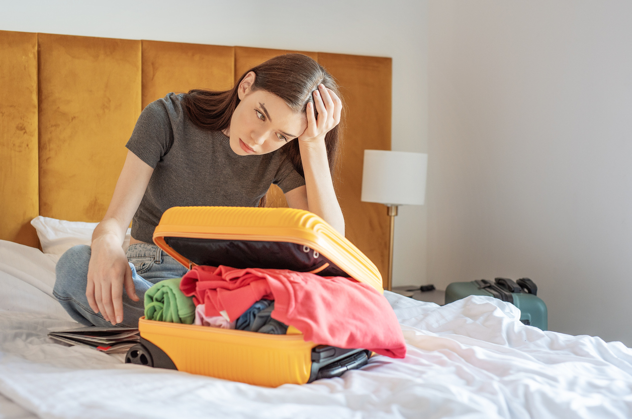 Traveler overpacking clothes into suitcase before vacation