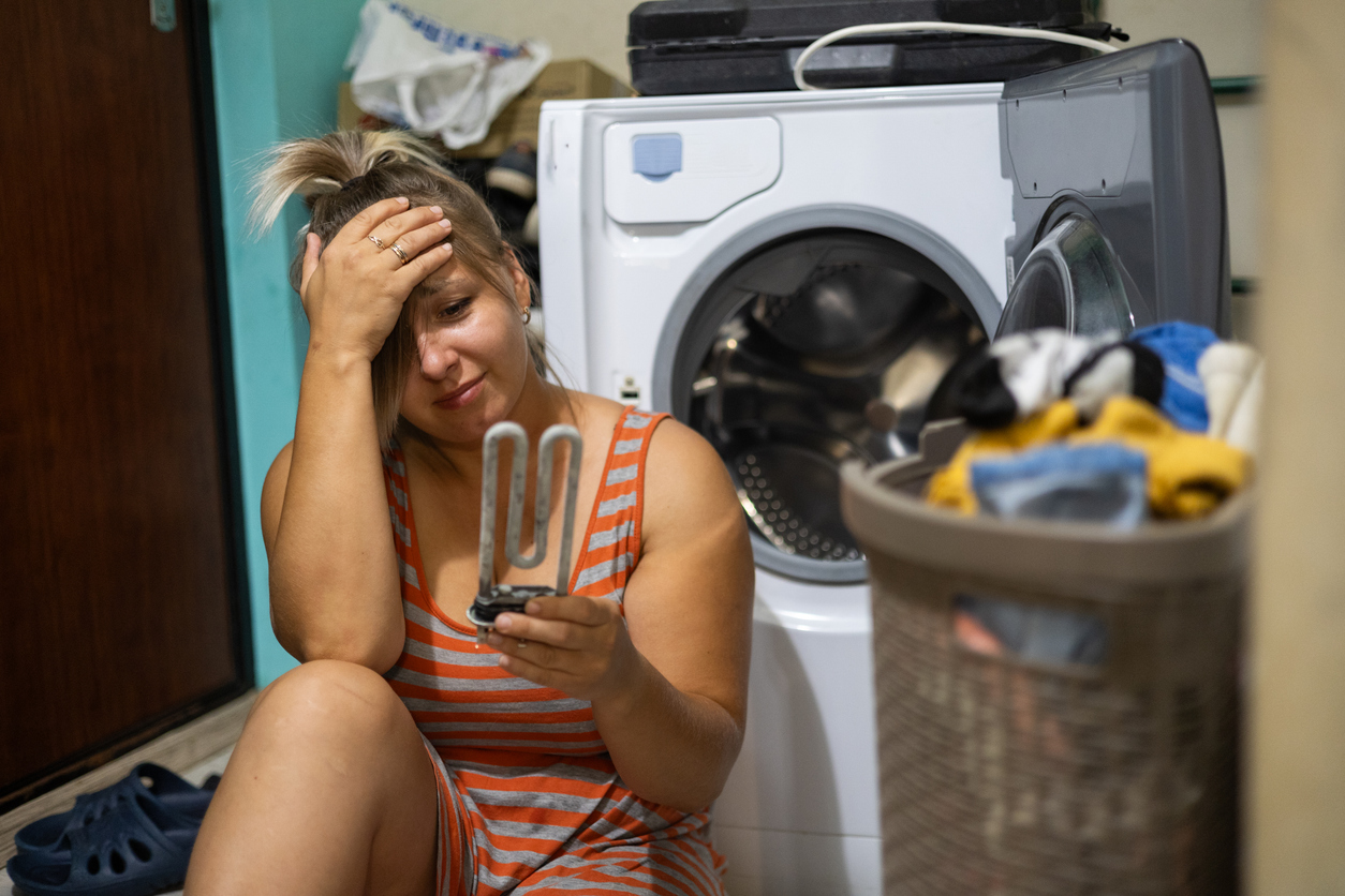 Woman frustrated with a broken washing machine while looking for alternative laundry solutions